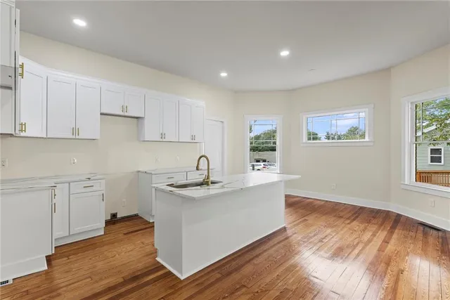 a kitchen with stainless steel appliances granite countertop a sink dishwasher a stove and white countertops with wooden floor