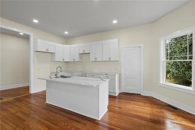 a kitchen with stainless steel appliances granite countertop a sink a stove a refrigerator and island with wooden floor