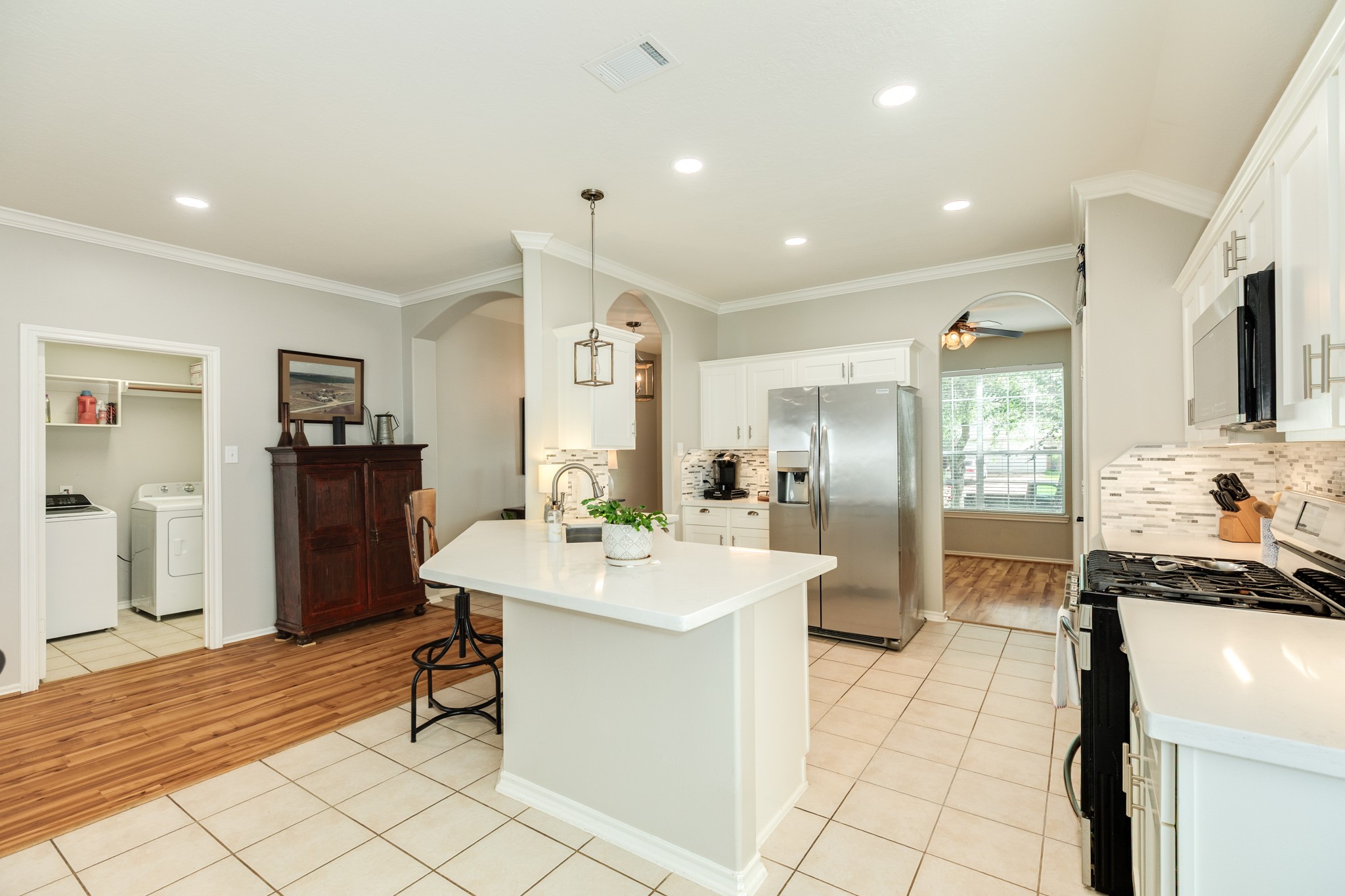 13808 Stark Bridge Lane Rosharon, TX 77583 - Photo 8 of 39 This view showcases the stunning designer backsplash that adds a sophisticated touch to the kitchen. The layout also highlights the convenient location of the laundry room, which provides direct access to the spacious two-car garage.