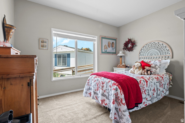 150 West 7500th South, Unit 13 Midvale, UT 84047 - Photo 21 of 32 Bedroom featuring neutral wall paint, carpet flooring, a white window frame, and a decorative headboard