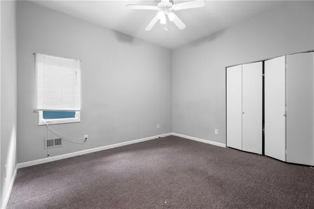an empty room with a chandelier fan and windows