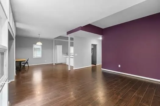 a view of an empty room with window and wooden floor