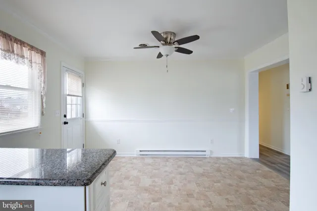 an empty room with chandelier fan and windows
