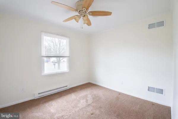 a view of an empty room and window with a chandelier fan