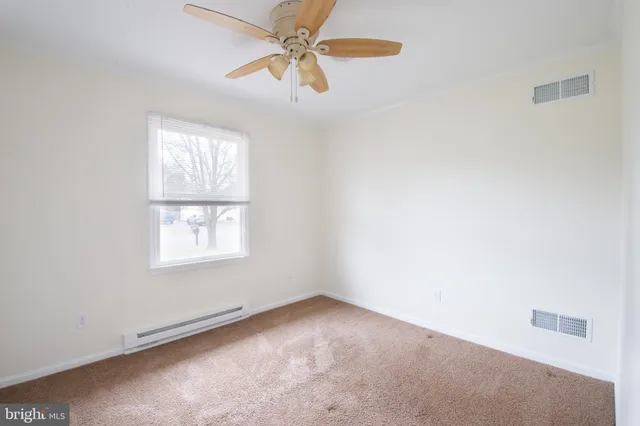 an empty room with windows and fan