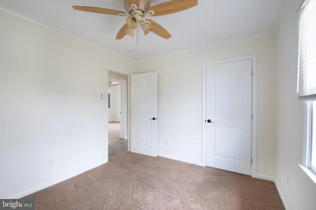 an empty room with windows and fan
