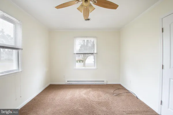 an empty room with windows and fan