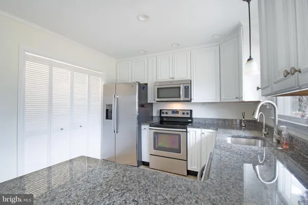 a kitchen with stainless steel appliances granite countertop a stove a sink and a microwave