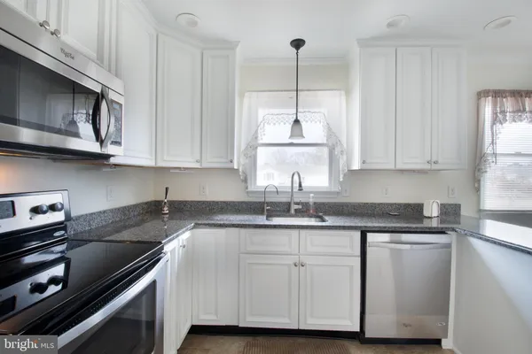 a kitchen with stainless steel appliances granite countertop a sink a stove and cabinets