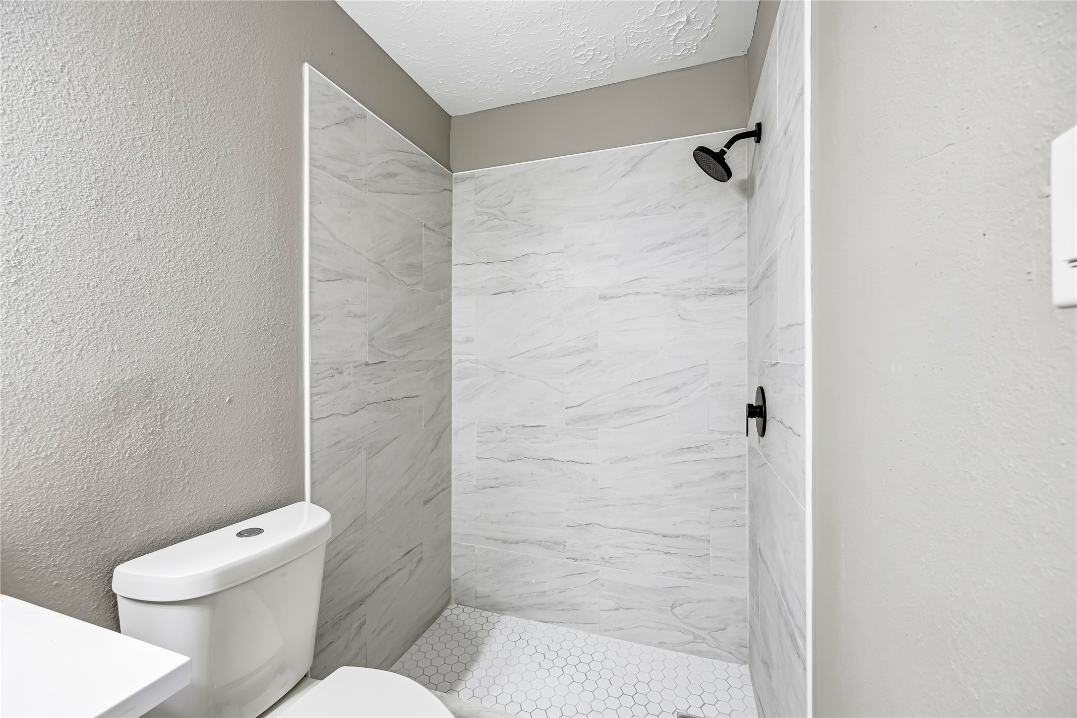 4534 Rosegate Drive Spring, TX 77373 - Photo 20 of 24 Updated bathroom featuring a walk-in shower with marble-look tile, hexagon tile flooring, and modern matte black fixtures. The neutral finishes create a clean, contemporary look with a bright and polished feel.