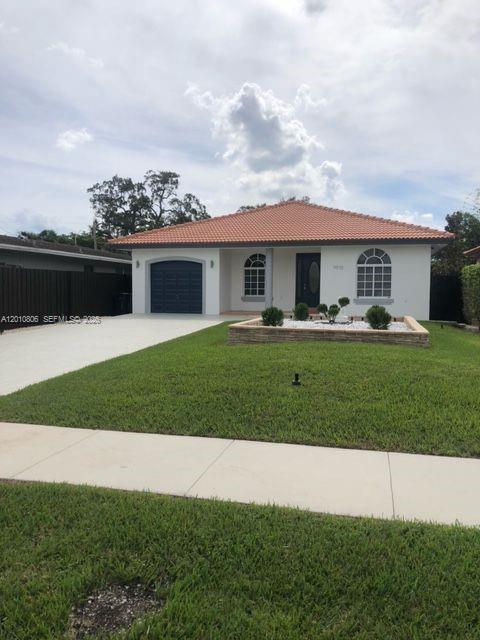 9910 Southwest 23rd Street Miami, FL 33165 - Photo 2 of 39 a front view of a house with a garden and yard