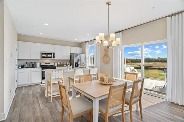 a view of a dining room and livingroom with furniture wooden floor a chandelier