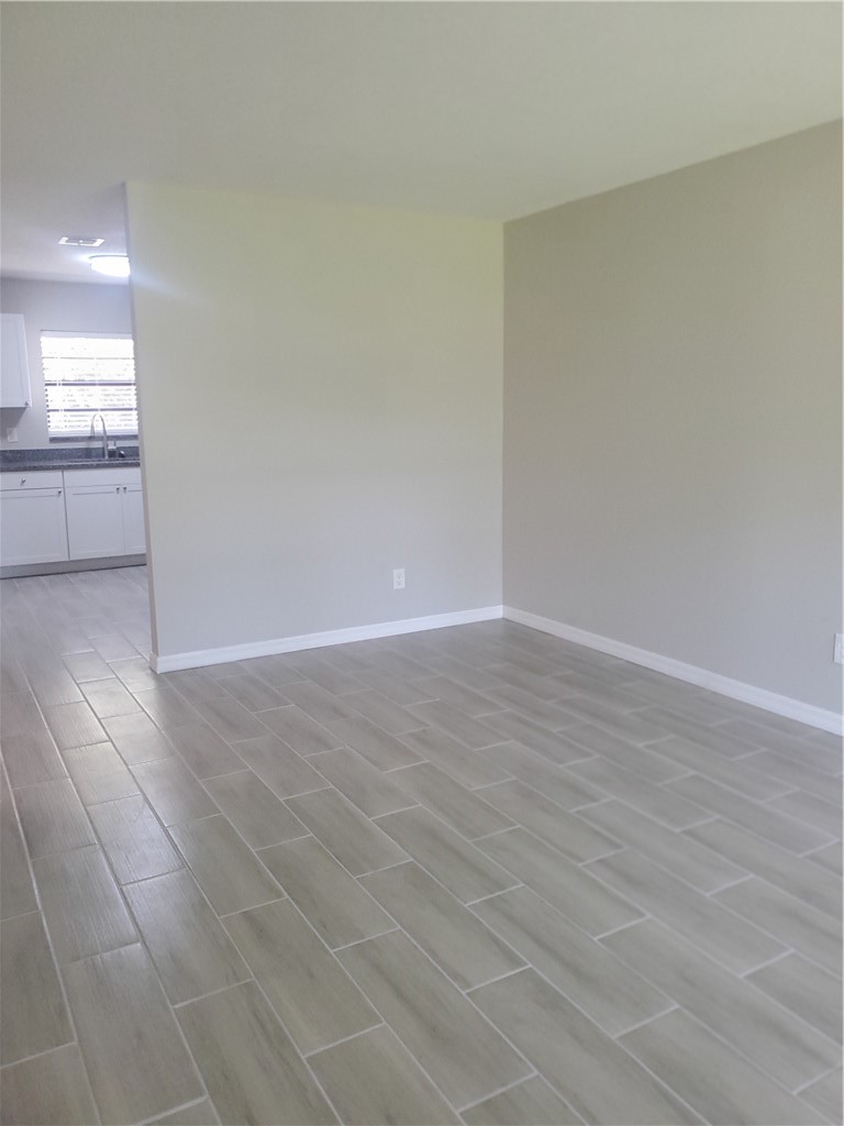 3300 South 7th Street, Unit B Fort Pierce, FL 34982 - Photo 12 of 32 an empty room with wooden floor and windows