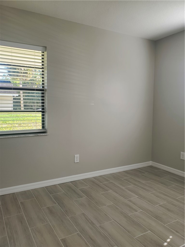 3300 South 7th Street, Unit B Fort Pierce, FL 34982 - Photo 18 of 32 an empty room with wooden floor and windows