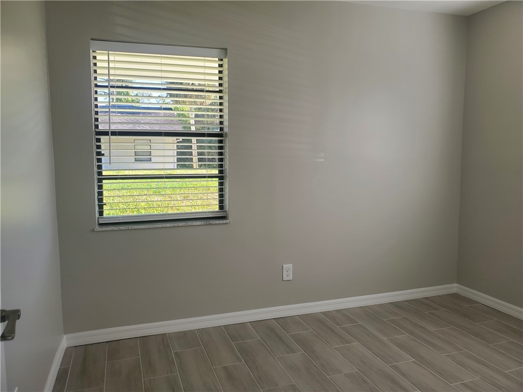 3300 South 7th Street, Unit B Fort Pierce, FL 34982 - Photo 21 of 32 a view of an empty room with wooden floor and a window