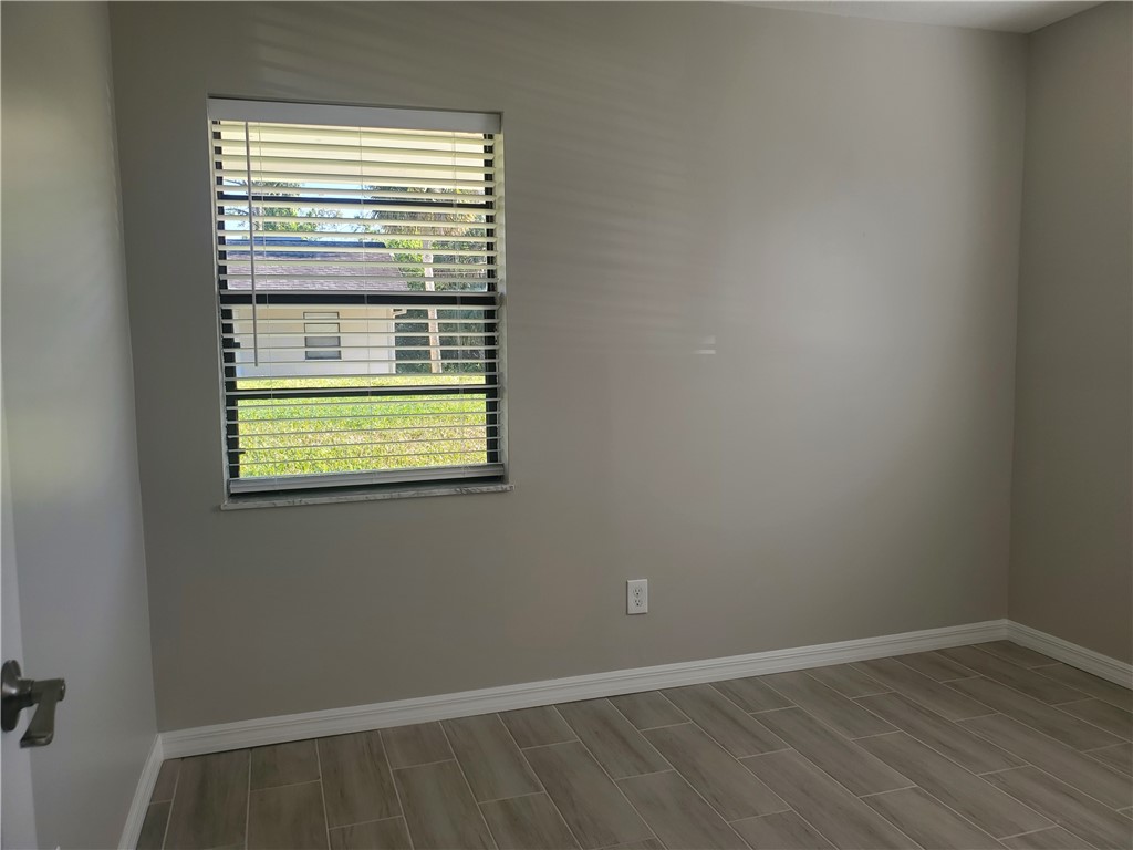 3300 South 7th Street, Unit B Fort Pierce, FL 34982 - Photo 22 of 32 a view of an empty room with wooden floor and a window
