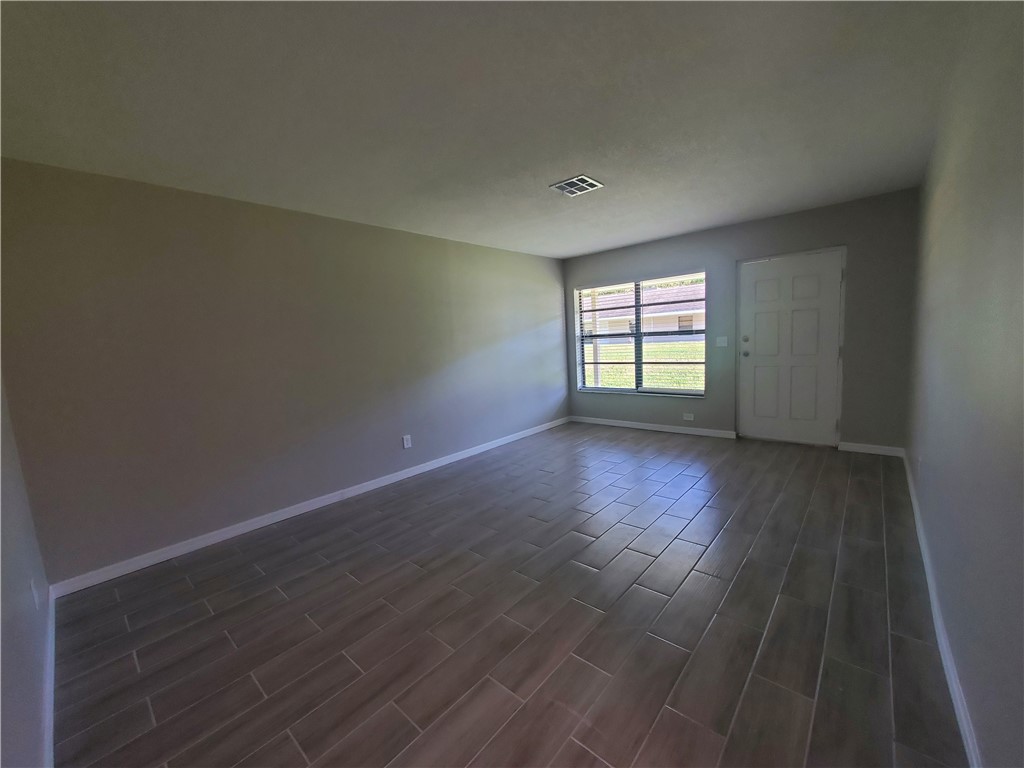 3300 South 7th Street, Unit B Fort Pierce, FL 34982 - Photo 27 of 32 an empty room with wooden floor and windows