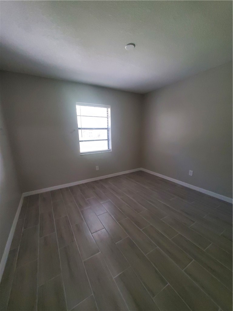 3300 South 7th Street, Unit B Fort Pierce, FL 34982 - Photo 28 of 32 an empty room with wooden floor and windows