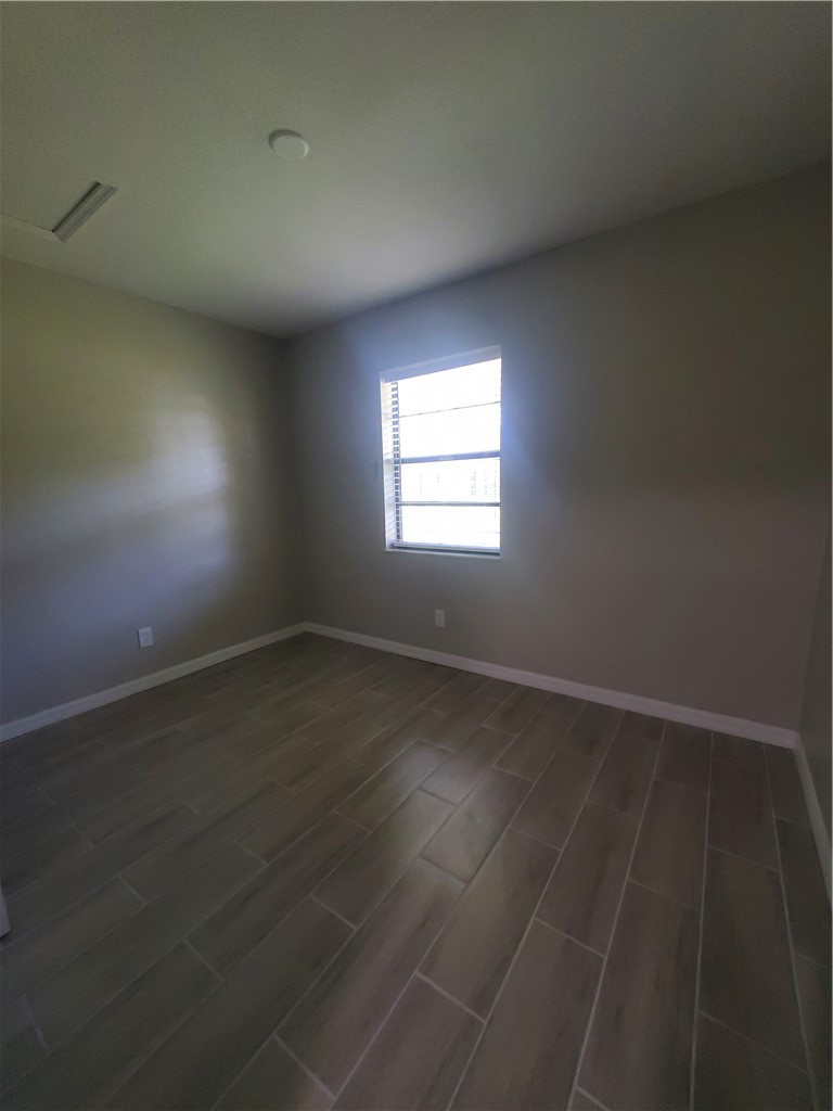 3300 South 7th Street, Unit B Fort Pierce, FL 34982 - Photo 29 of 32 an empty room with wooden floor and windows