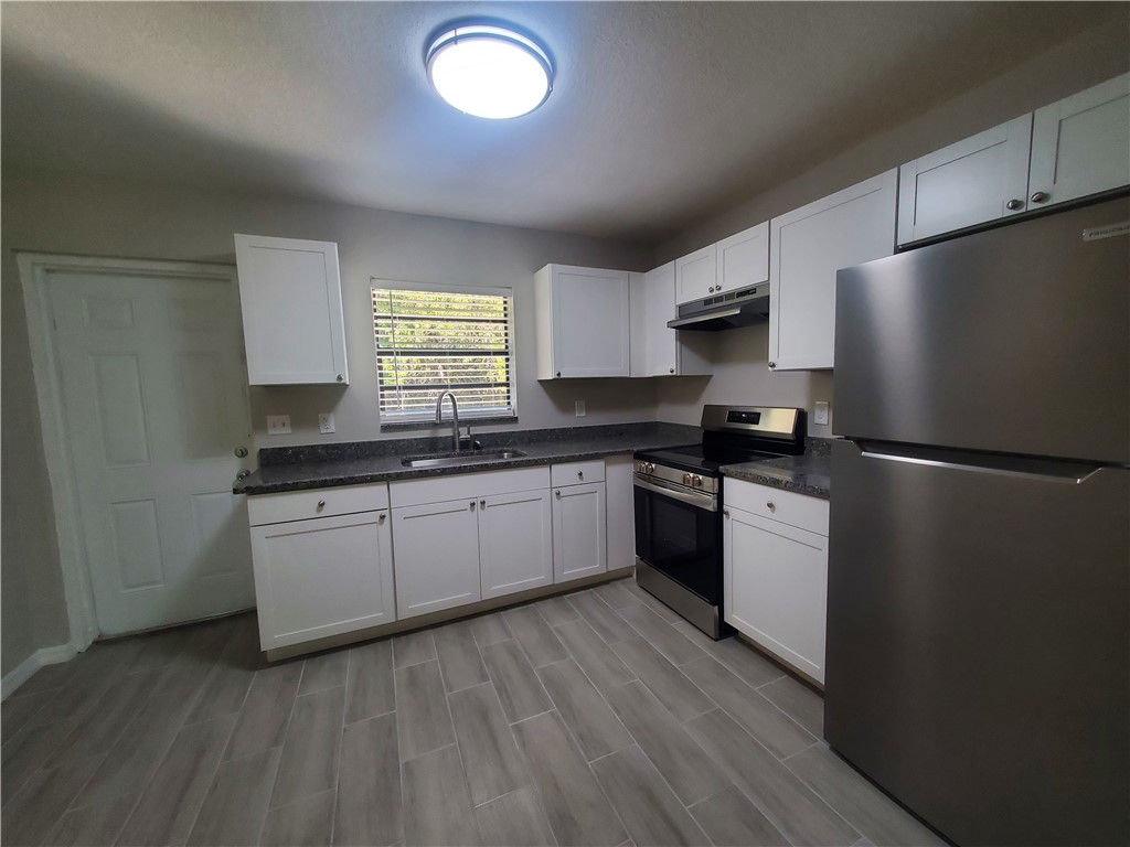 3300 South 7th Street, Unit B Fort Pierce, FL 34982 - Photo 6 of 32 a kitchen with granite countertop a refrigerator a sink dishwasher a stove and white cabinets