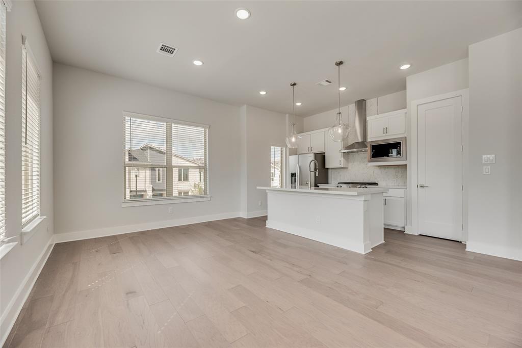 920 Ash Road Plano, TX 75075 - Photo 6 of 27 a view of kitchen with kitchen island a sink wooden floor and a stove top oven