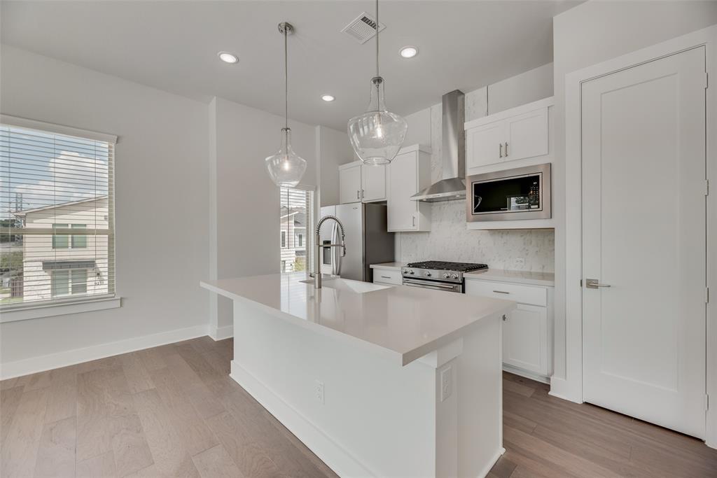 920 Ash Road Plano, TX 75075 - Photo 8 of 27 a kitchen with kitchen island a white counter top space a sink and a stove