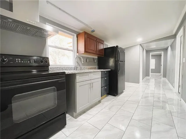 a view of a refrigerator in kitchen and an empty room in wooden floor