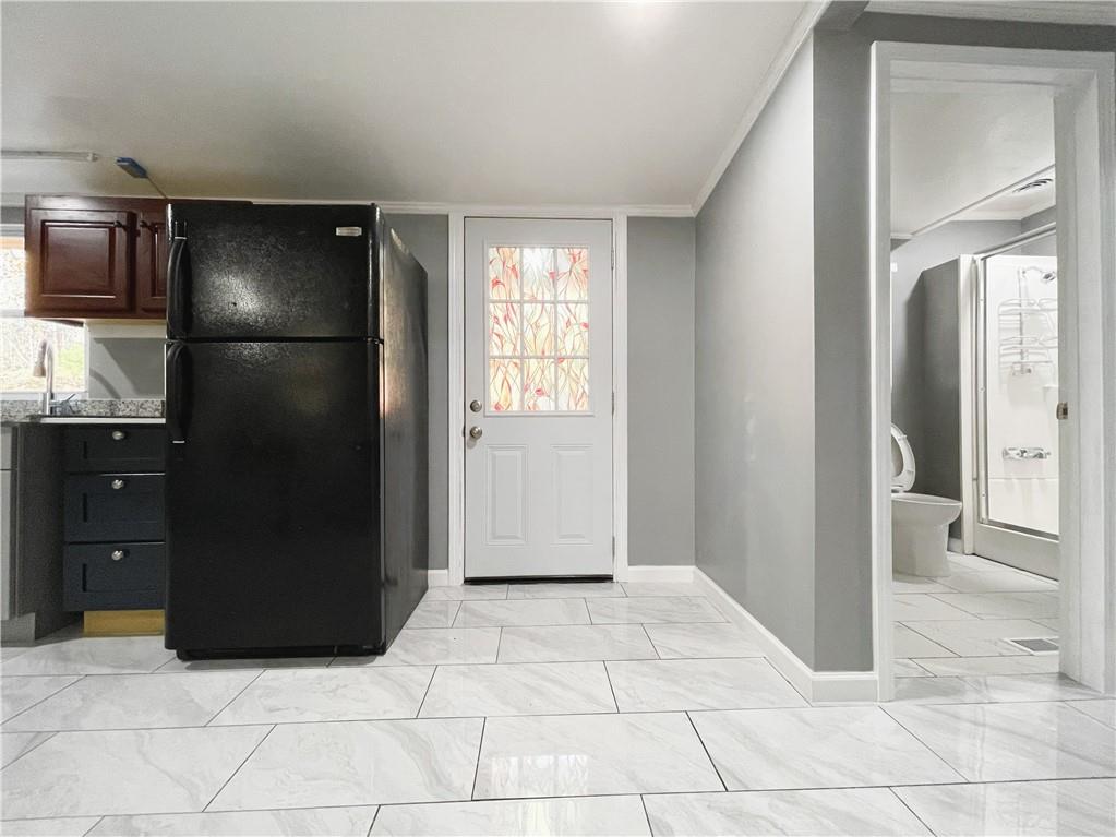 6225 Lollis Creek Road Flowery Branch, GA 30542 - Photo 29 of 36 a view of a refrigerator in kitchen and an empty room in wooden floor
