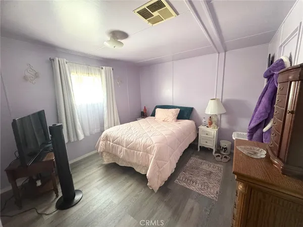 a bedroom with a bed a flat screen tv and a window