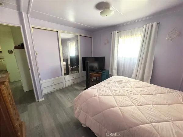 a bedroom with a bed and a flat tv screen on dresser