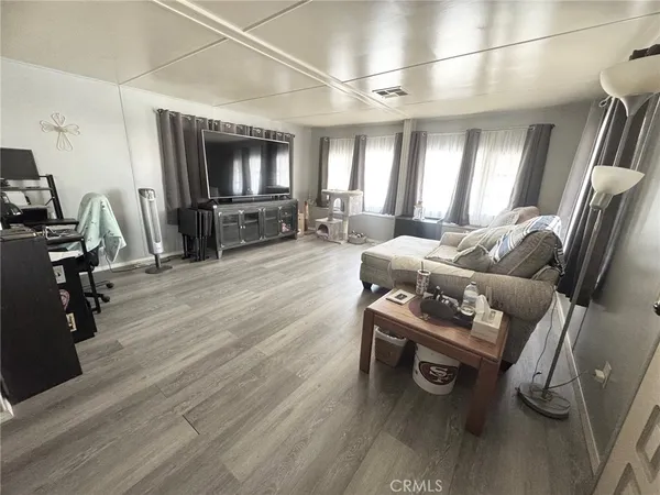 a living room with furniture a flat screen tv and a wooden floor