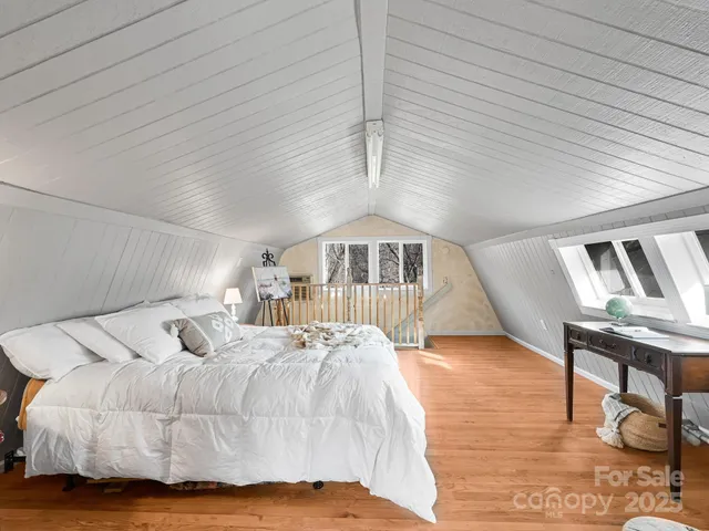 a bed sitting in a spacious bedroom next to a larger window