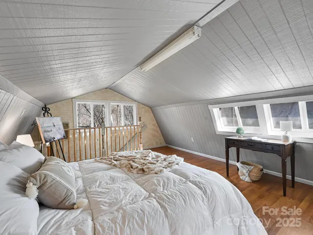 a bed sitting in a bedroom next to a window with wooden floor