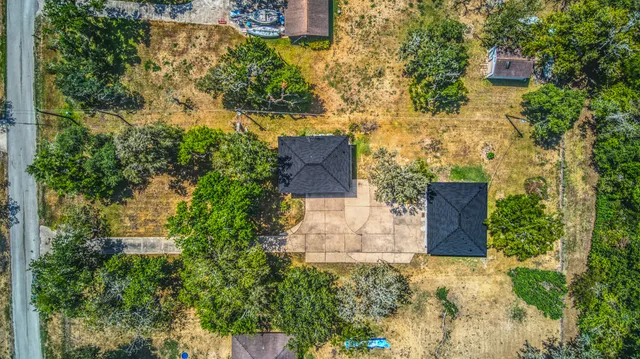 an aerial view of a house with a yard and large tree