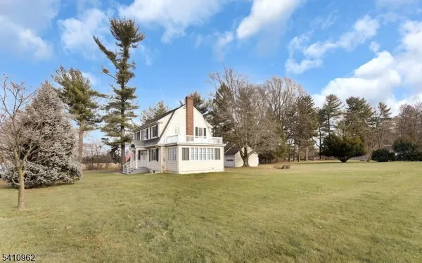 a view of white house with a big yard and large trees