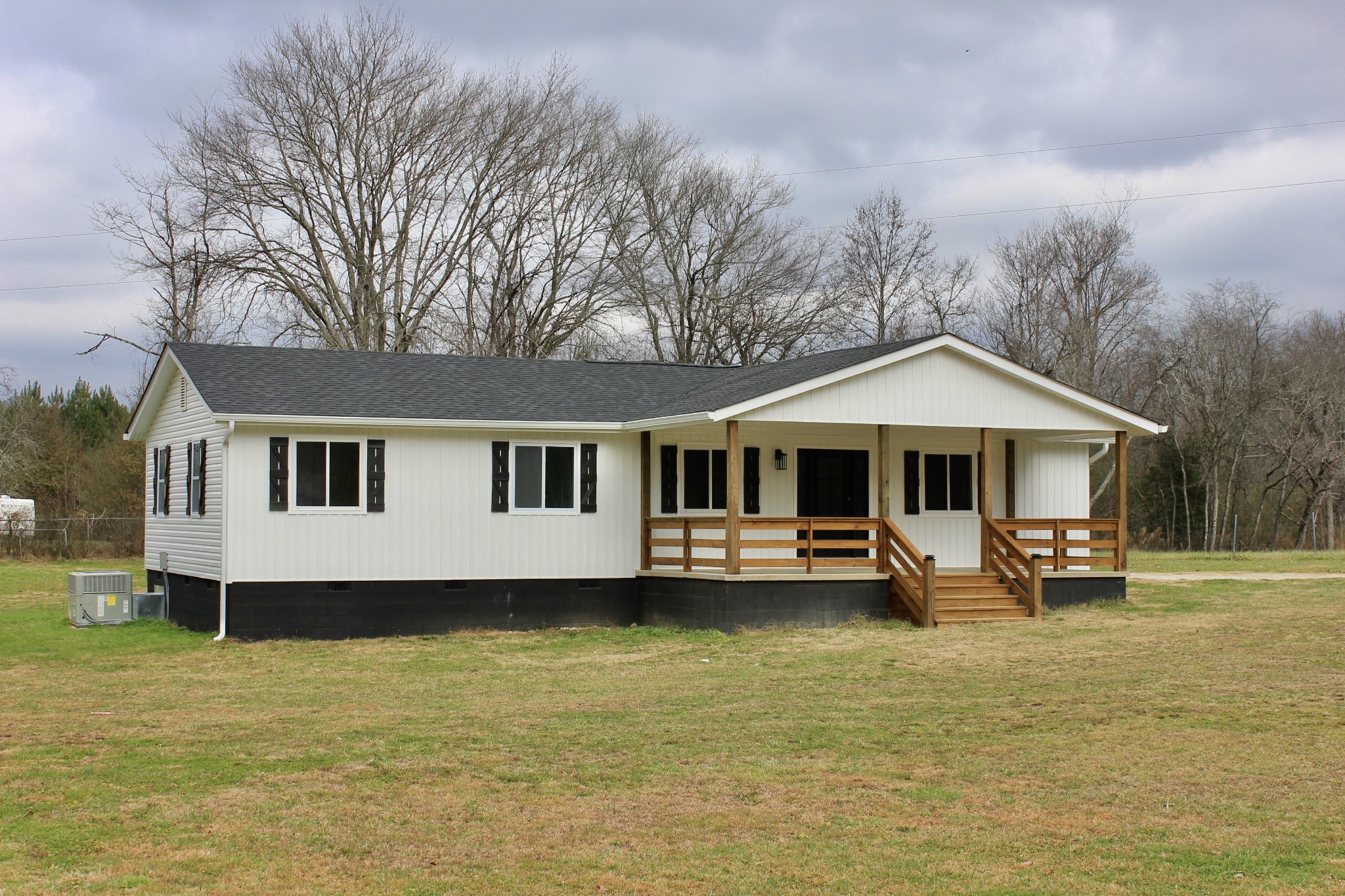 a front view of a house with a wooden deck and a yard