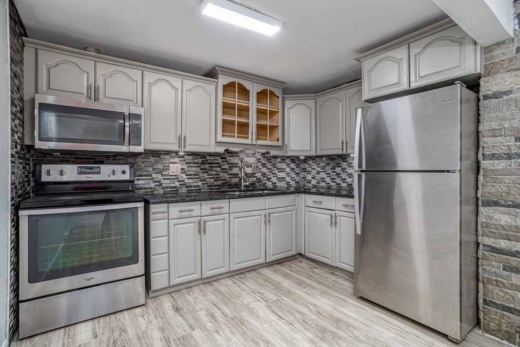 39 Berlin Street, Unit 315 Clinton, MA 01510 - Photo 3 of 22 a kitchen with stainless steel appliances granite countertop a refrigerator stove a sink and dishwasher with wooden floor