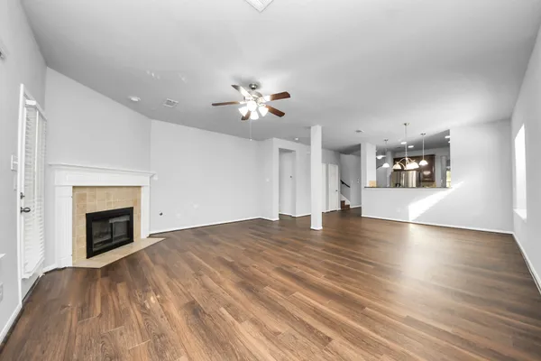 a view of an empty room with chandelier fan and fire place