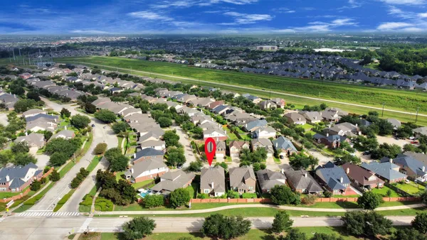 an aerial view of residential houses with outdoor space and trees