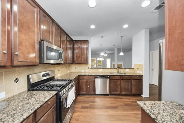 a large kitchen with stainless steel appliances granite countertop a stove and a sink