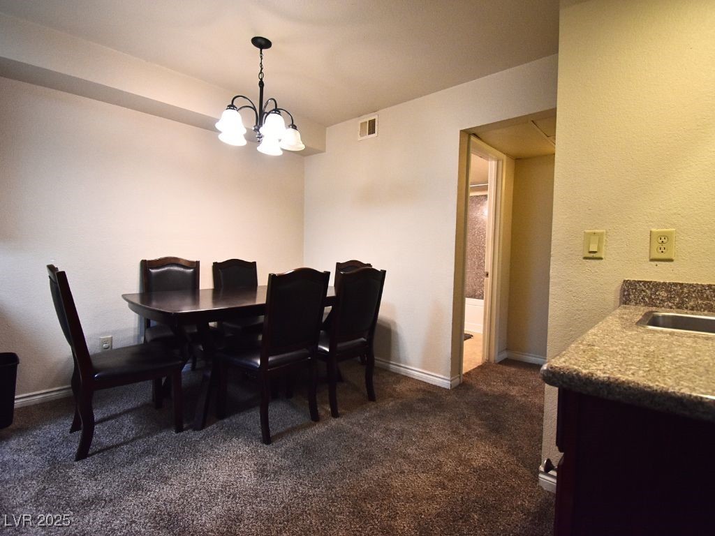 2451 North Rainbow Boulevard, Unit 1130 Las Vegas, NV 89108 - Photo 11 of 21 Dining space with dark colored carpet, a chandelier, and a textured wall