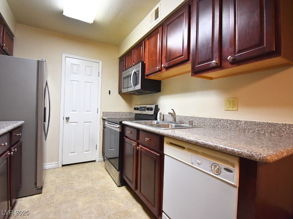 2451 North Rainbow Boulevard, Unit 1130 Las Vegas, NV 89108 - Photo 10 of 21 Kitchen featuring stainless steel appliances, dark brown cabinets, light tile patterned floors, and light countertops