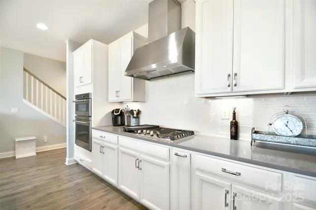 a kitchen with stainless steel appliances granite countertop a stove and a white cabinets