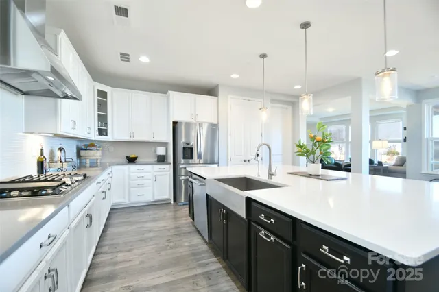 a large kitchen with a large counter top a sink stainless steel appliances and cabinets