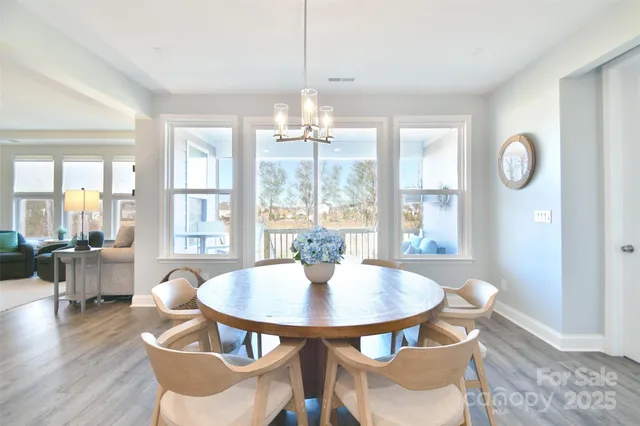 a dining room with furniture a chandelier and wooden floor