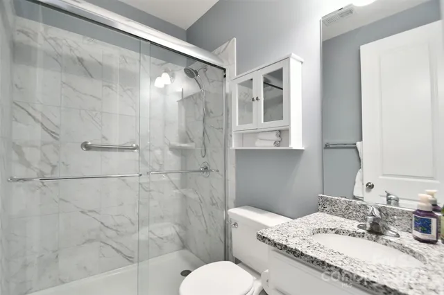 a bathroom with a granite countertop sink toilet a mirror and shower