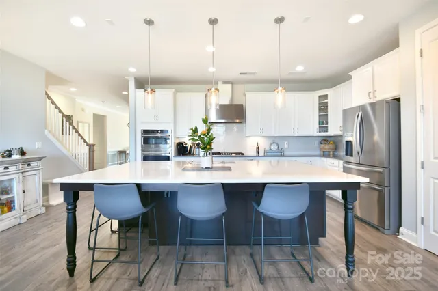 a kitchen with stainless steel appliances granite countertop a table chairs sink and cabinets
