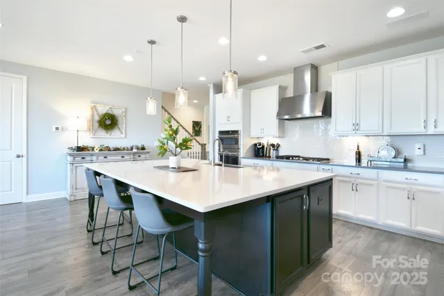 a kitchen with kitchen island stainless steel appliances a sink a stove a table and chairs