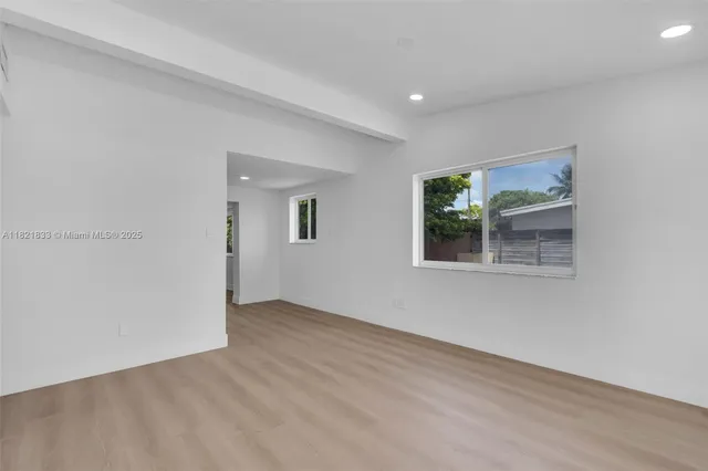 an empty room with wooden floor and window