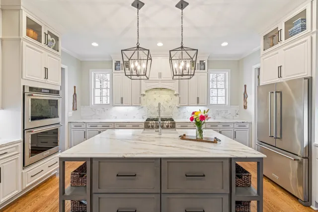 a living room with stainless steel appliances kitchen island granite countertop a table chairs and a refrigerator